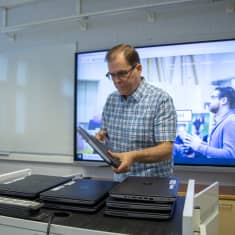 Rehtori Pekka Manninen nostaa kannettavia tietokoneita pöydälle