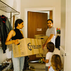 Ayla Urus perheineen kantaa muuttolaatikoita kotiinsa.