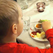 Lapsi syö ravintolassa ruokaa.