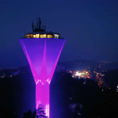 Ilmakuva Lahden vesitornista, mikä valaistu värikkäillä värivaloilla.