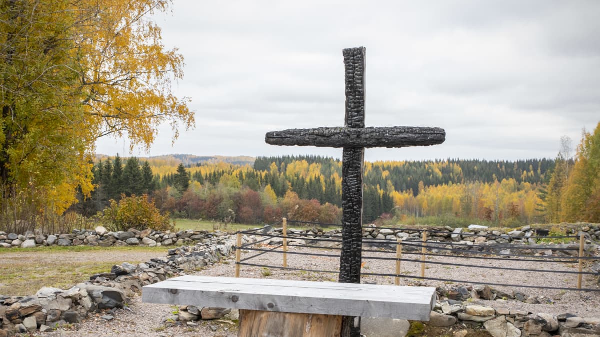 Palaneista hirsistä tehty risti ja alttari ruskaisessa maisemassa.