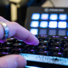 Närbild på fingrar som trycker på ett tangentbord som lyser.