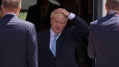 Boris Johnson astuu oviaukosta pidellen päätään.