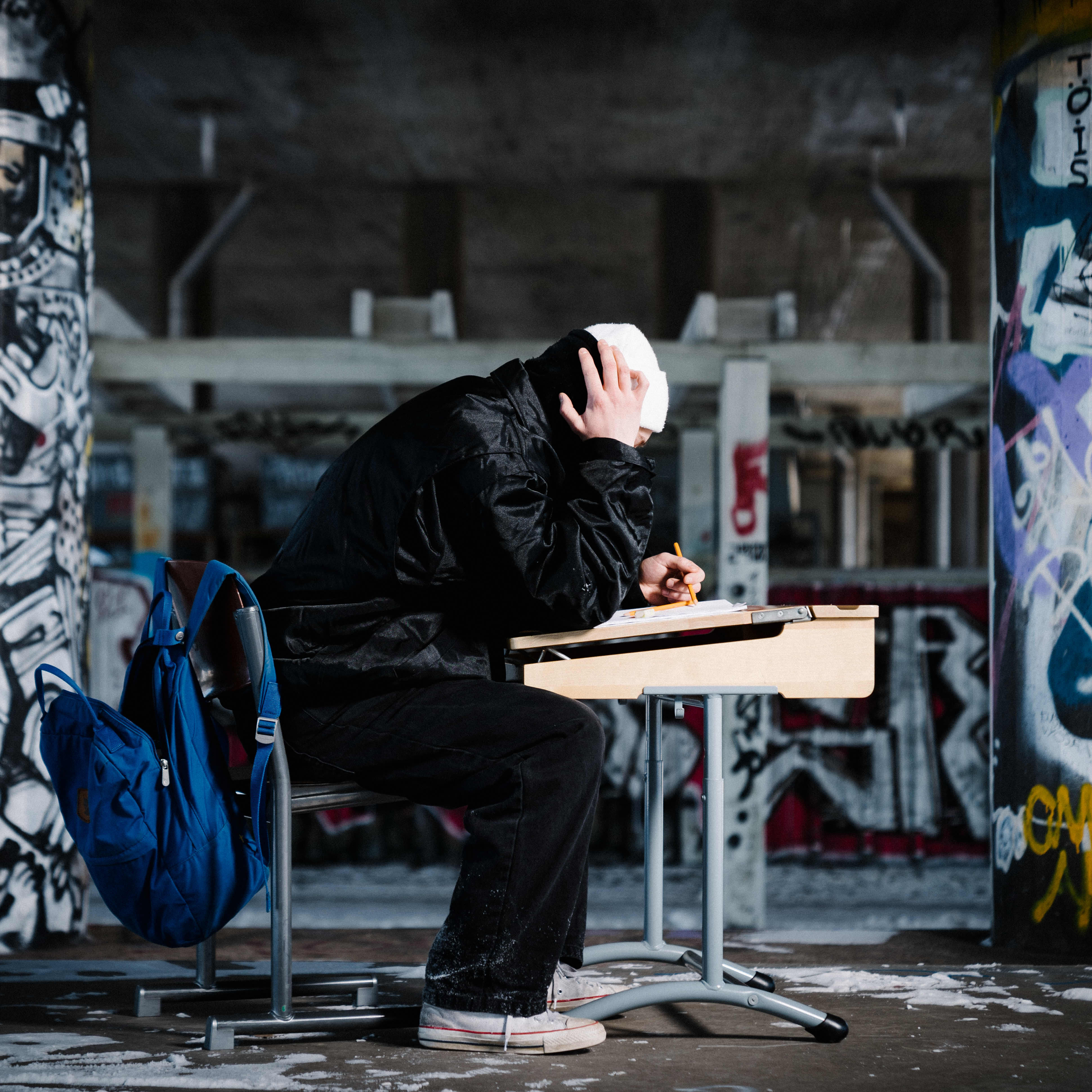 kuvituskuva nuori istuu yksin pulpetin ääressä graffitien ympäröimänä