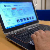 En bärbar dator med en hand på tangentbordet. På datorns skärm är Raseborgs stads hemsida öppen. 