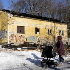 Ohikulkijoita ohittaa palanutta taloa.
