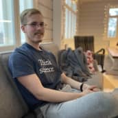 Antti Asikainen iloisena sohvalla, päällään t-paita jossa lukee Think Science. 