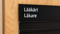 Lääkärikyltti ovessa suomeksi ja ruotsiksi.