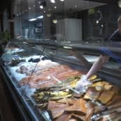 Myyjä järjestelee kaloja myyntitiskissä vaasalaisessa kalakaupassa.