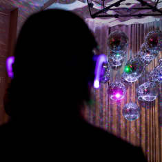 Kansallismuseossa Silent Discossa kuuntelee kuulokkeilla henkilö musiikkia discopallojen loisteessa.