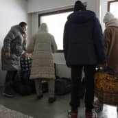 Juuri saapuneet pakolaiset kantavat kasseja huoneeseen Salmirannan vastaanottokeskuksessa Jyväskylässä. 