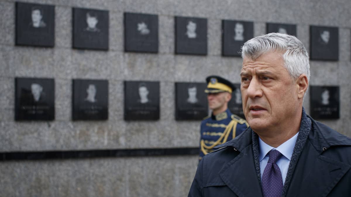 Kosovos president Hashim Thaçi tittar på ett monument.