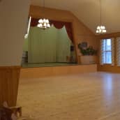 En tom sal med scen i ett föreningshus.
