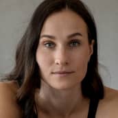 Miia Sillman katsoo suoraan ja hänellä on vakava ilme. Sillmanin päällä on musta toppi ja hiukset ovat auki.