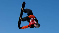 Rene Rinnekangas ilmassa Pekingin olympialaisten slopestylen karsinnassa. Suomalainen on parhaillaan pyörimisliikkeessä ja ottaa grabin lautansa pohjasta.