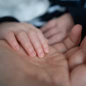 Pikkuvauvan käsi äidin kämmenellä.