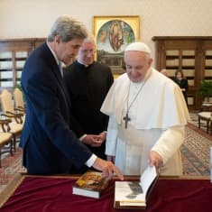 John Kerry osoittaa kirjan sivua paaville.