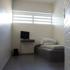 Poliisivankilan selli, jossa vaalet seinät, betoninen sänky, patja, peitto ja tyyny. Takaseinän yläreunassa ikkuna jossa vahvat kalterit.