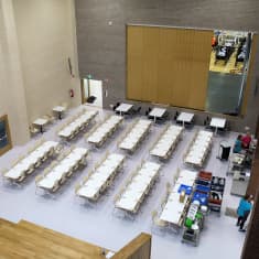 Ylhäältä päin otetussa kuvassa näkyy valkoisia pöytiä ja tuoleja. 