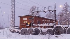 Tegelhus bland elstolpar i snöigt landskap. 