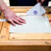 Äänestäjä laittaa vaalikuorta äänestyslaatikkoon.