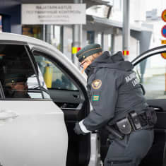 Rajavartija tarkastaa henkilöautoa rajanylityspaikalla.