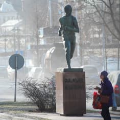 Liikenne nostattaa pölyä Turun keskustassa Paavo Nurmen patsaan ympärillä.