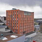 Punavärinen kahdeksankerroksinen rakennus seisoo muiden rakennusten keskelleä Turun Kupittaalla. 