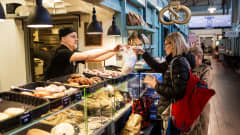 Kauppahallin Leipomon Tapani Ojala ojentaa asiakkaalle leipomo-ostokset mukaan ennen vappua huhtikuussa 2020.