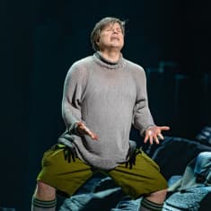 Siegfried-oopperan näyttämöllä tenori Daniel Brenna eläytyy rooliinsa levittäen kämmenet ylöspäin ja katsoen ylöspäin.