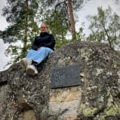 Mustasaarelainen Paula Jaskari istuu ison kiven päällä vanhan kyläkoulunsa pihalla.