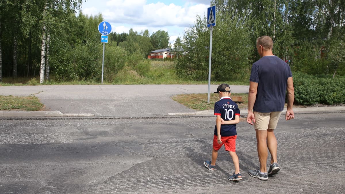 Isä ja poika ylittävät tien pojan koulumatkalla