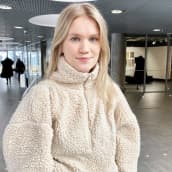 Nainen seisoo yliopiston käytävällä.