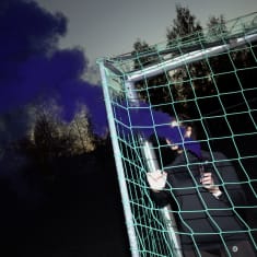 Jalkapallomaali ja henkilö jolla on kädessä violettia savua tuottava putki.