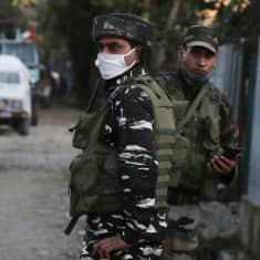 Kaksi aseistettua Intian turvallisuusjoukkoihin kuuluvaa miestä partioi kadulla Kashmirissa, toisella kasvomaski