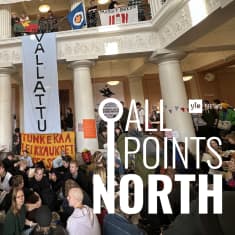 The lobby of University of Helsinki's main building filled with protesters and decorated with banners.
