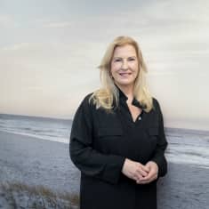Elina Kivioja seisoo suuren hiekkarantaa esittävän taulun edessä.