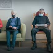 Neljä ikäihmistä istuu sohvalla tabletit käsissään ja maskit kasvoillaan. Yksi heistä näyttää älypuhelimesta toiselle jotakin.
