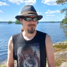 Tuomas Holopainen seisoo järvenrantamaisemassa