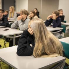 Tyttö nojaa pulpettiin koululuokassa.