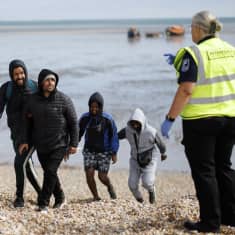 En grupp flyktingar tar sig iland i Dungeness Beach i Kent efter att han räddats från en liten båt ute i Engelska kanalen