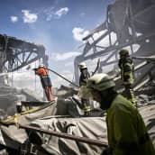 Pelastustyöntekijät sammuttavat tuhoutunutta rakennusta.