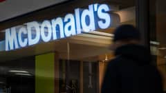 Nuori kävelee McDonalds's mainoskyltin alta.