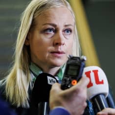 Foreign Minister Elina Valtonen speaking in front of microphones held by press.