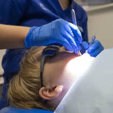Hammaslääkäri tutkii hoitovälineillä lapsen hampaita.