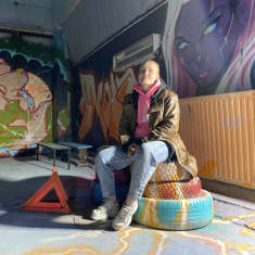 Nuori nainen istuu graffitein koristellussa huoneessa rengaspinon päällä.