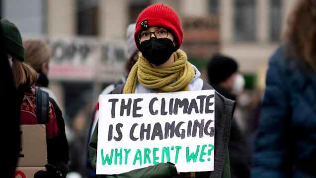 En person håller i en skylt där det står "The climate is changing, why aren't we?" på en klimatprotest.