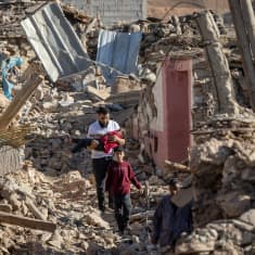 Mies kantaa lasta Marokossa, talo on sortunut