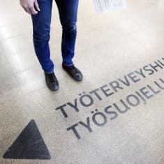 Työterveyshuolto -opastekyltti maalattuna lattiaan.