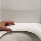 Hand som vilar mot toalettkrans.